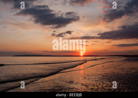 View of the sun setting over Camber Sands and the English Channel in England UK. Stock Photo