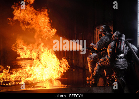 Firefighters  extinguish a simulated battery fire inside an aircraft fire trainer at Royal Air Force Mildenhall, England. Stock Photo