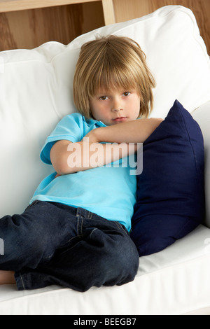 Young Boy Sat on Sofa at Home Stock Photo