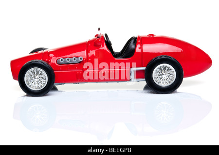 Old fashioned red toy racing car on a white background with reflection. Stock Photo