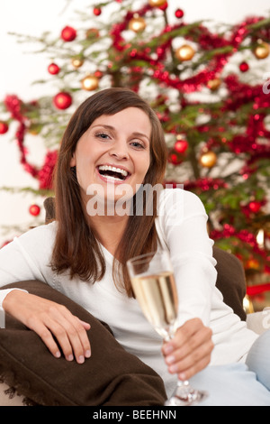 Christmas - Brown hair woman sitting with glass of champagne on Christmas in front of tree Stock Photo