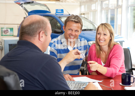 Couple filling in paperwork in car showroom Stock Photo