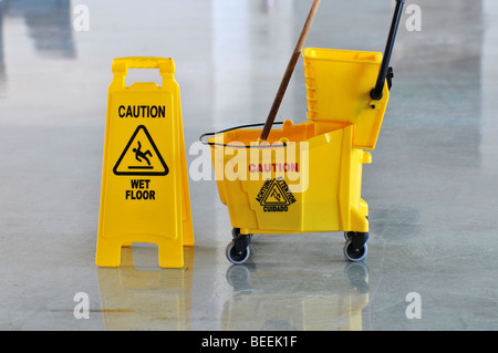 Mop bucket and caution sign on wet floor Stock Photo