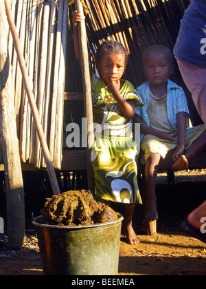 Madagascar - Children wait to help with the dung mixing for a fuel efficient stove at Ebakika Village Stock Photo