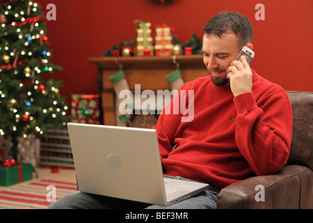Man with laptop and cell phone, home decorated for Christmas Stock Photo