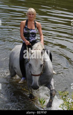 Outdoor photo of the young lady riding on the horse Stock Photo