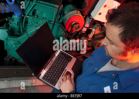 Motor mechanic using computer to set up and diagnose a coach engine Stock Photo