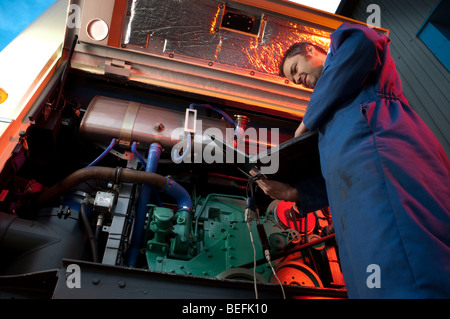Motor mechanic using computer to set up and diagnose a coach engine Stock Photo