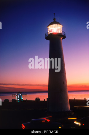 The Old Biloxi Lighthouse on Gulf of Mexico in Mississippi with passing traffic at dusk Stock Photo