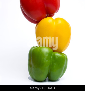 Three peppers, a red, a yellow and a green on a white background in studio. Stock Photo