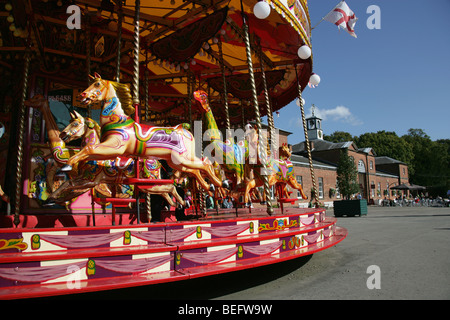 Estate of Tatton Park, England. A funfair carousel at Tatton Park stable yard with the Stables Restaurant in the background. Stock Photo