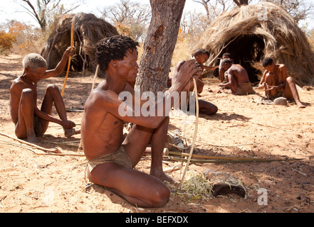 San Village. Manufacturing a bow and arrow the traditional way. Attaching the bow string to the bow. Stock Photo