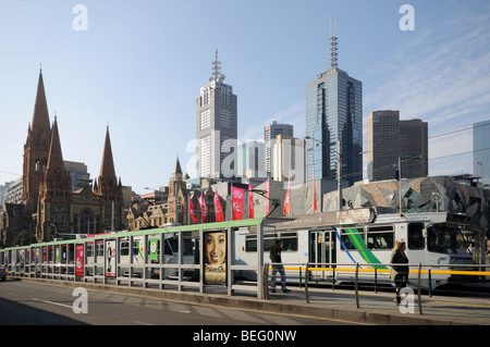 Trams and tram stop on Princes Bridge over Yarra River Melbourne Australia with St Pauls Cathedral and high rise skyscrapers Stock Photo