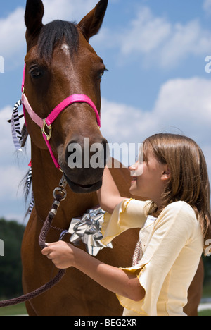 A little girl looking with joy and affection at a beautiful horse that has been given to her as a gift on her birthday. Stock Photo