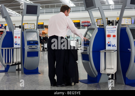 Departing passenger use British Airways self-service check-in kiosks at Heathrow Airport's Terminal 5. Stock Photo
