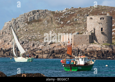 Yacht and fishing boat with Cromwell’s Castle in the background, viewed from Bryher, Isles of Scilly Stock Photo