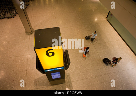 Aerial view of passengers towing wheelie baggage in the baggage reclaim hall in the arrivals of Heathrow Airport's T5 Stock Photo