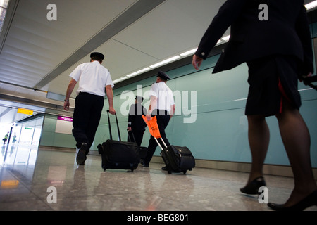 Arriving British Airways flight deck and cabin crew stride through arrivals after long-haul flight to Heathrow Airport's T5 Stock Photo