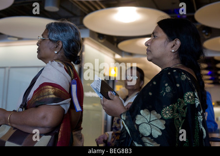 Airline passengers from India await transit instructions in line at Heathrow Airport's Terminal 5 arrivals concourse. Stock Photo