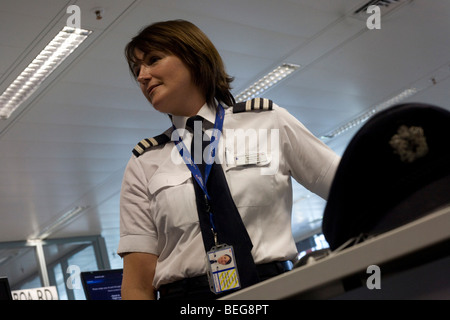 A lady pilot examines flight data and documents in the British Airways Crew Report Centre at Heathrow Airport's T5 Stock Photo