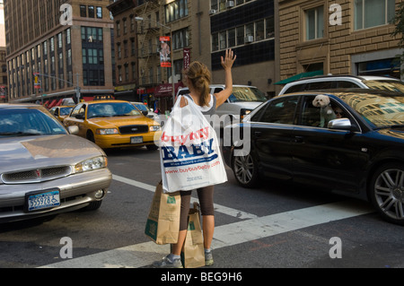 A shopper attempts to hail a taxicab in the trendy Chelsea neighborhood in New York Stock Photo