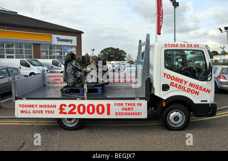 Nissan car dealer pickup truck carrying a crushed old car as promotion for government car scrappage scheme Essex dealership England UK Stock Photo
