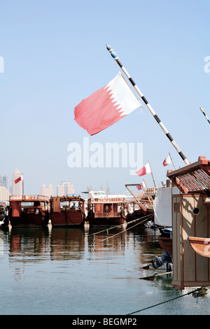 A view of the dhow harbour in Doha, Qatar, with the focus on Qatar's national flag. Stock Photo