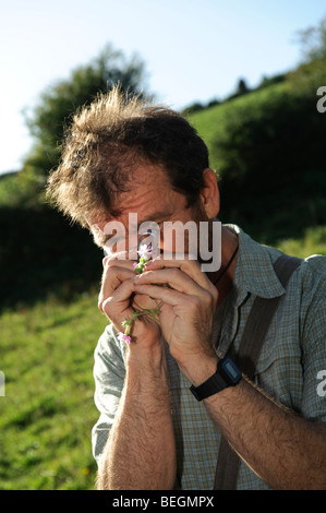 Andy Jones, a  botanist with the Countryside Council for Wales looking at a plant through a hand held magnifying glass lens Stock Photo