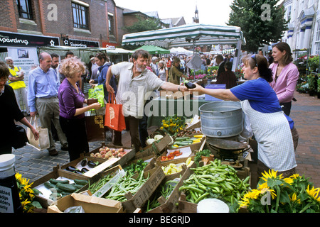 Buying an aubergine at a vegetable stall at Lewes farmers' market, Lewes, East Sussex. Stock Photo