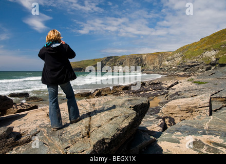 A tourist taking a photograph of the view at Trebarwith Strand in Cornwall, England, UK Stock Photo