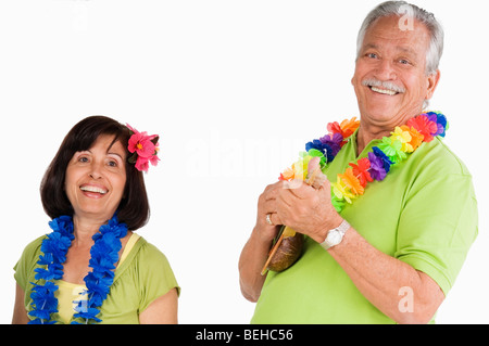 Senior man playing ukulele with a senior woman dancing beside him Stock Photo