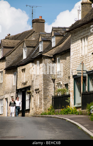 Couple walking in a street of Bisley, Gloucestershire, UK Stock Photo