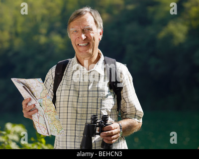 senior hiker holding map and binoculars and looking at camera. Copy space Stock Photo