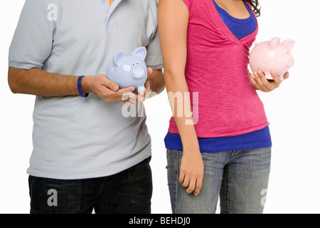 Mid section view of a young couple holding piggy banks Stock Photo