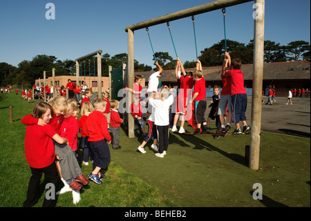 Young children at break-time playing on climbing ropes in playground on a sunny day in a Welsh language medium primary school Stock Photo