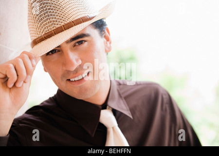 Portrait of a young man tipping hat and smiling Stock Photo
