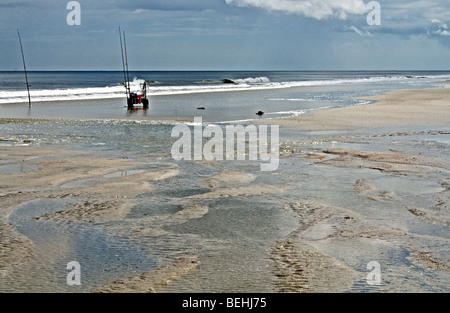 Fishing pole, cooler, sandals and bait bucket on a beach in Florida Stock Photo