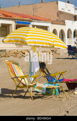 Two Empty Beach Chairs and A Striped Sun Parasol On The Beach Stock Photo