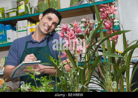 Male sales clerk taking order in a flower shop and smiling Stock Photo
