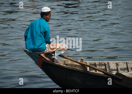 A boatman sits on the bow of his boat, a ferry used to transport villagers in rural Bangladesh. Stock Photo