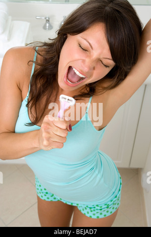 Young woman singing into a razor Stock Photo