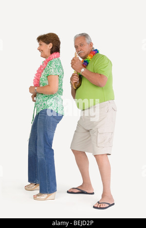Senior man playing ukulele with a senior woman dancing in front of him Stock Photo