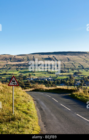 Winding road Yorkshire Dales England UK with warning sign for skidding Stock Photo