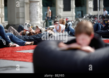 People read while lying on beanbag cushions at an outdoor library in the Hauptplatz in the city of Graz in Austria Stock Photo