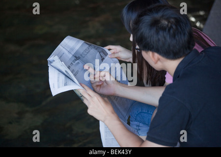 Young Koreans Reading a Newspaper at Cheonggyecheon River in Seoul South Korea Stock Photo