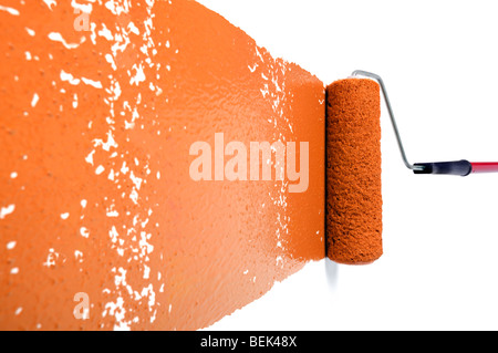 Pain roller with orange paint on white wall Stock Photo