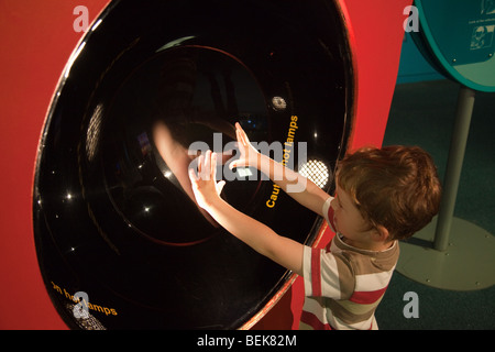 Boy trying shake your own hand exhibit in Xperiment gallery of Museum of Science and Industry (MOSI), Liverpool Road, Manchester Stock Photo