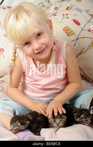 Stock photo of a little 4 year old girl playing with her kittens. Stock Photo