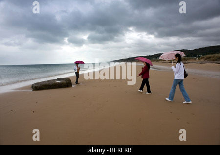 Omaha Beach, Normandy, France. Tourists visit Remains of WW2 D Day German blockhouse ruins on beach. Stock Photo