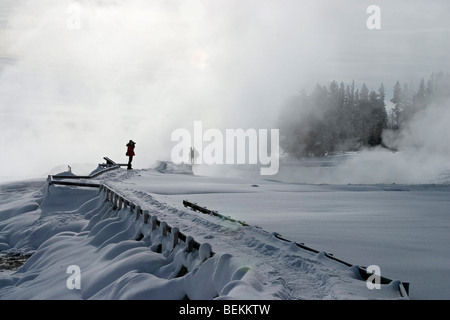 Visitors on boardwalk trail in fog at West Thumb in Yellowstone National Park in winter. Stock Photo